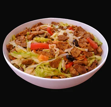 Donair salad with donair beef, lettuce, tomato and olives in a white bowl