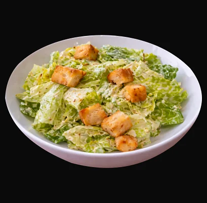 Caesar salad with romaine, croutons and creamy dressing in a white bowl