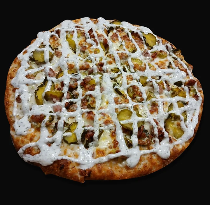 Pickle pizza with sliced pickles and a lattice of white sauce