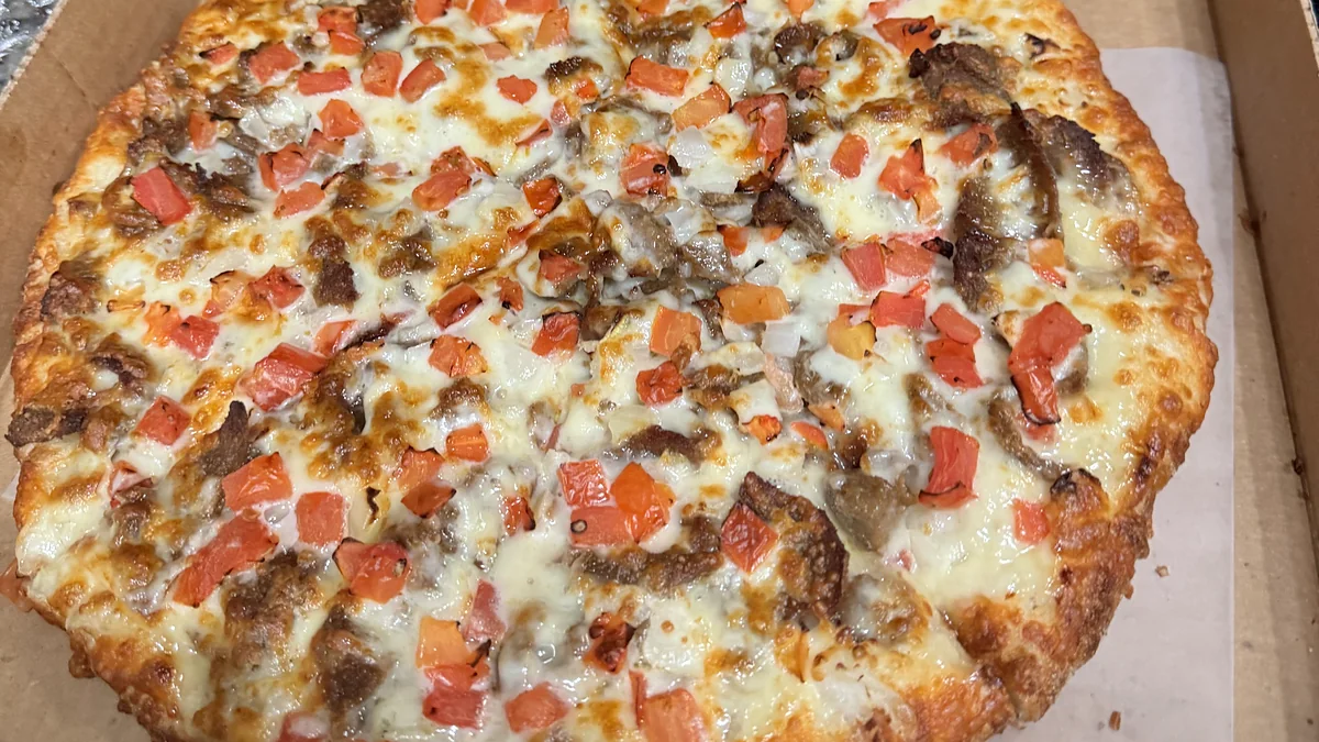 Donair pizza topped with donair beef, diced tomato and melted cheese in an open pizza box