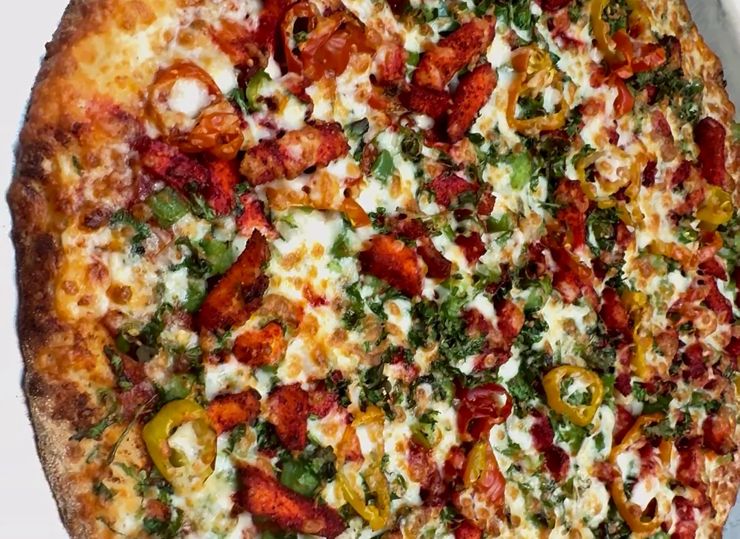 Thin-crust pizza topped with red and green peppers and melted cheese on a silver tray
